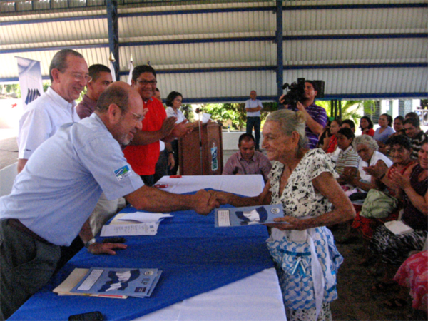 Doña María Araceli Mejía, residente de la Comunidad Casa de la Estación, recibe su escritura.