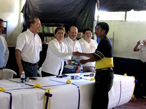 La Gobernadora Departamental de La Unión, Sra. Xenia Elizabeth López entrega una de las 35 escrituras de las familias de Meanguera del Golfo. De izquierda a derecha (en mesa de honor): Viceministro de Vivienda, Sr. José Roberto Góchez; Gobernadora departamental. Director Ejecutivo del ILP, Sr. David Henríquez y Representante de Asamblea Legislativa, Sr. Iván Herrera.