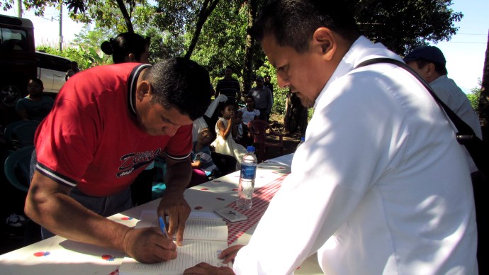 Familias de la comunidad Nueva Agua Zarca, en San Juan Opico, firman su escritura de propiedad, que los acredita como legítimos propietarios del lote en el que habita.