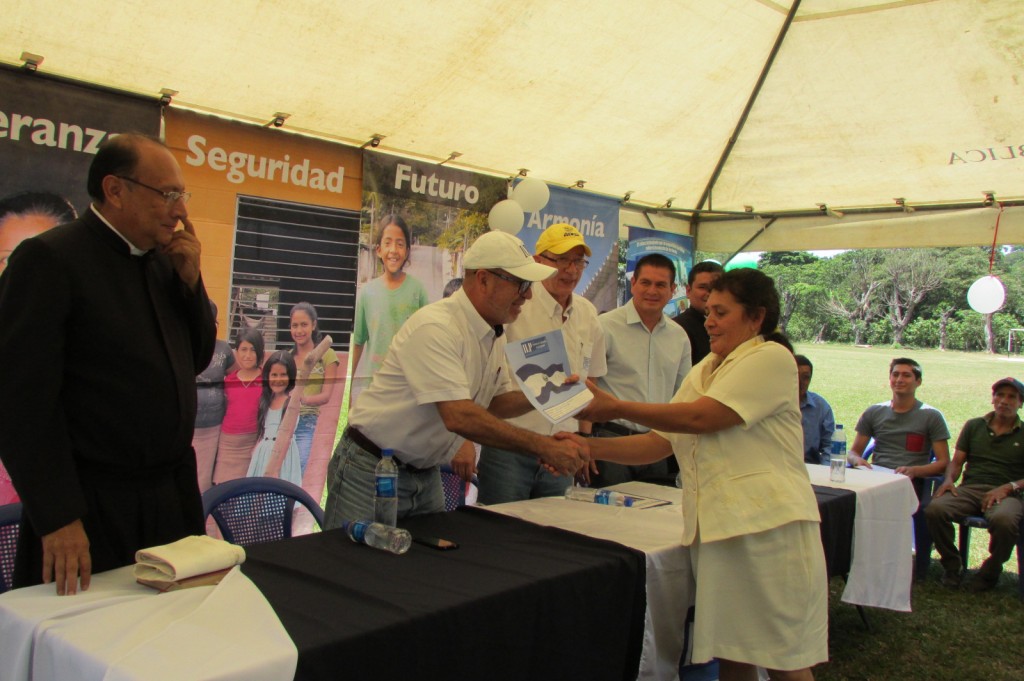 La señora Justina Mar Gómez recibe escritura de propiedad de manos del Director Ejecutivo del ILP, Ing. David Henríquez.