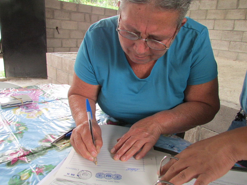 Familias de la comunidad Dr. Guillermo Manuel Ungo I y II, en Suchitoto, firman su escritura de propiedad, que los acredita como legítimos propietarios del lote en el que habita.